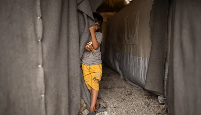 Child next to a tent in ICRC camp in Greece