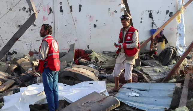 Two Red Crescent workers stand amidst the wreckage caused by an explosion
