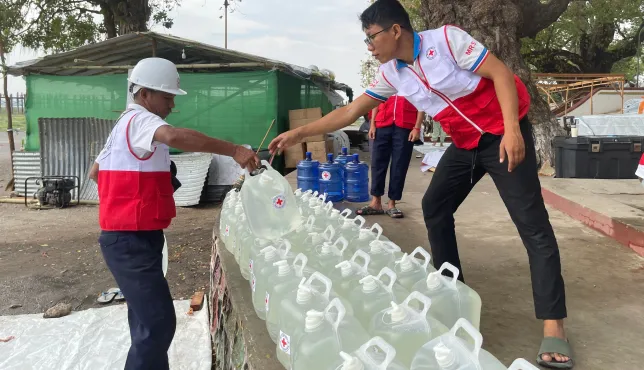 ICRC workers providing clean water containers in Myanmar