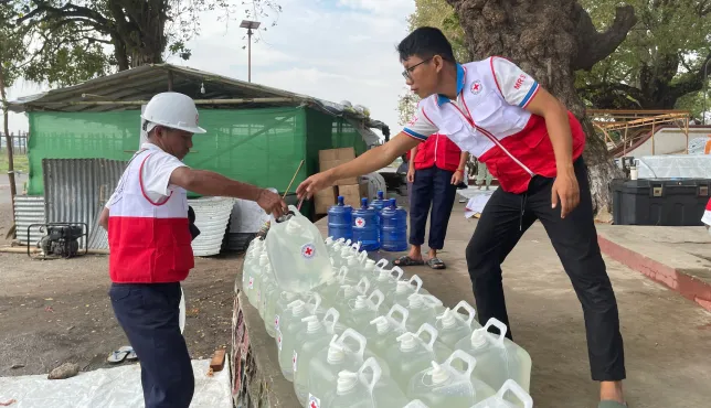 ICRC workers providing clean water containers in Myanmar
