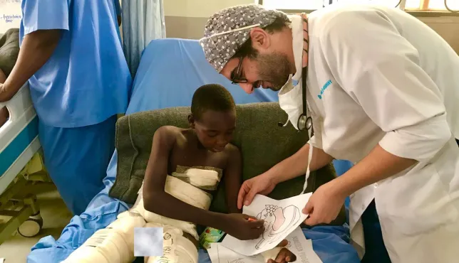 Egyptian anesthesiologist Dr. Aktham Al-Farnawani encourages a child to color after he was injured in an explosion in Maiduguri, Nigeria.