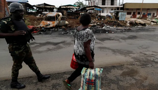 A woman walks past a Cameroonian elite Rapid Intervention Battalion (BIR) member in the city of Buea in the anglophone southwest region, Cameroon 