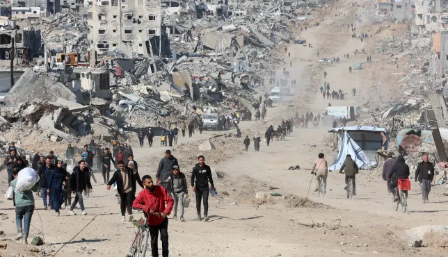 Palestinians walk in a street in Jabalia along the rubble of destroyed buildings as the displaced head to the northern areas of the Gaza Strip, on the third day of a ceasefire deal in the war between Israel and Hamas, on January 21, 2025.