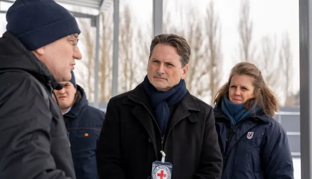 ICRC Director-General Pierre Krähenbühl speaks with a local resident outdoors in a winter setting, accompanied by a colleague.