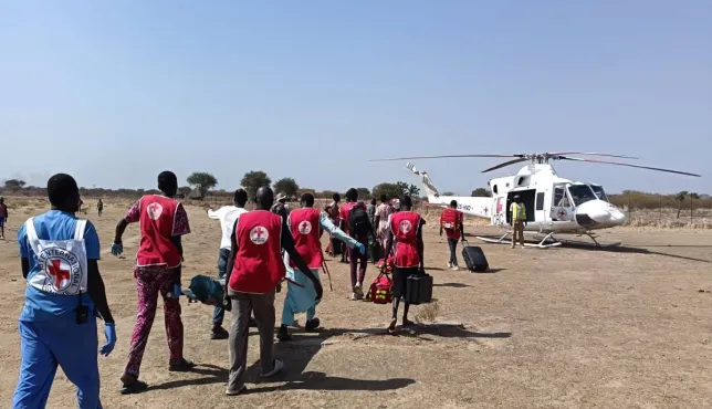 A group of South Sudan Red Cross volunteers, accompanied by an ICRC health personnel, carrying a weapon-wounded patient on a stretcher towards an evacuation aircraft to be airlifted for further treatment. Photo Credit Greta Mancassola/ICRC.
