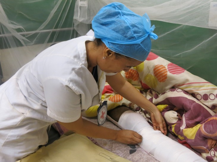 Azahara ajuste le pansement d'un patient qui se remet d’une opération. 