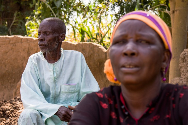 Adana Dilya and his wife sit outside their burnt-out home. The ICRC is helping them rebuild.