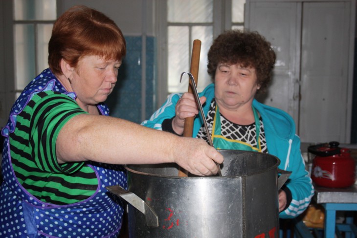 The cooks in the summer camp ladle out tea for their visitors.