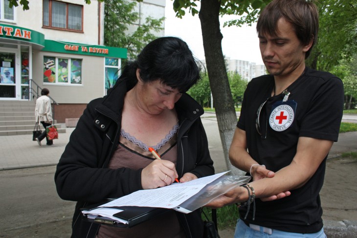 Ruslana writes a reply leaning on Arkadiy’s folder.