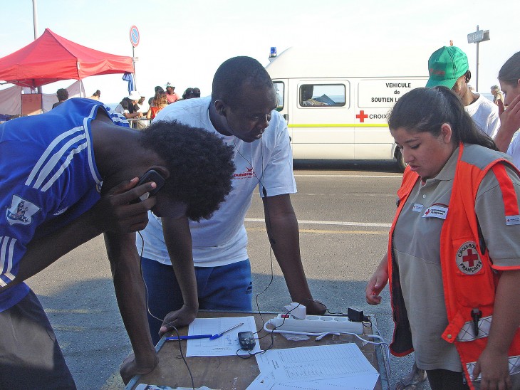 Two migrants call home on phones provided by the French Red Cross. 