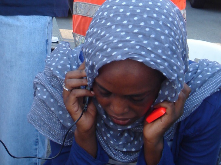 A woman strains to hear the familiar voice of a far-away family member among the noise and bustle of a French Red Cross aid point. 