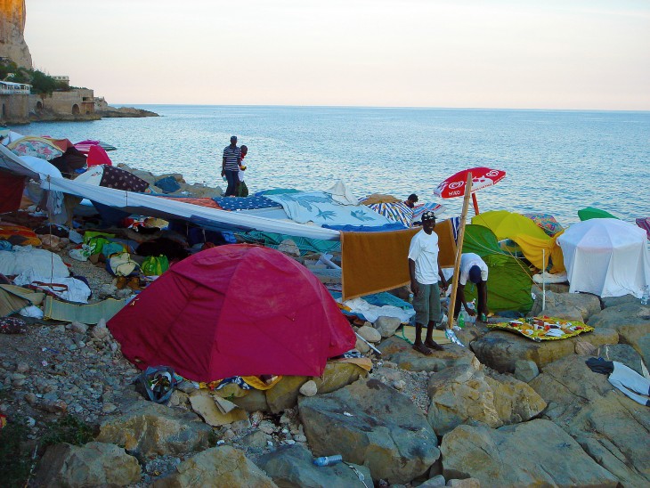 Migrants wait at an improvised encampment.