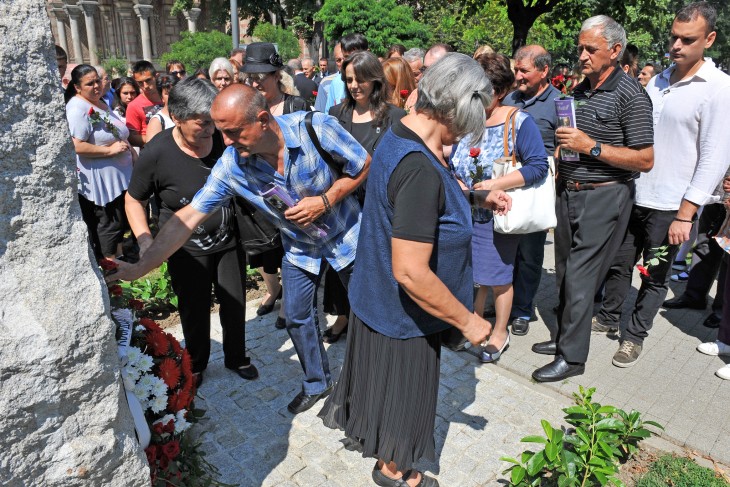 Families of missing persons lay flowers on a memorial monument.