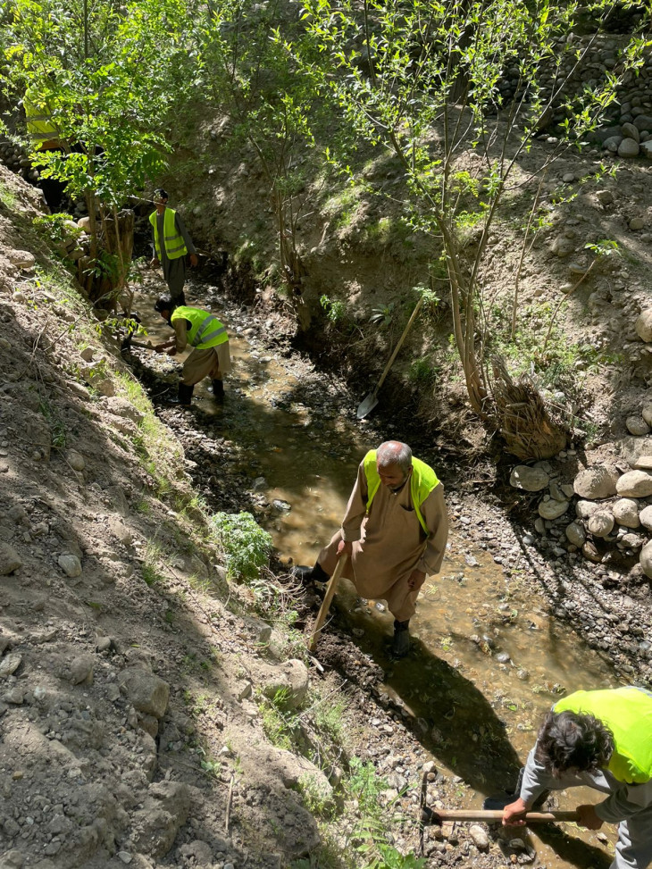 Workers clear out dirt and stones from an irrigation canal to allow a smooth flow of water to irrigate the fields. Abdul Wahid Sediqy/ICRC
